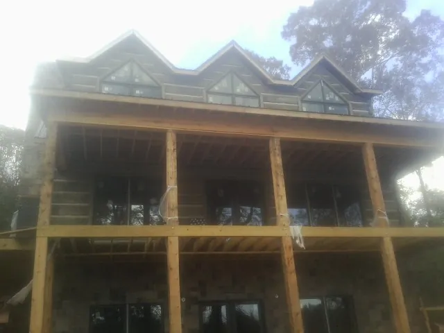 Dormers and porch framing on a large log home under construction — Roof Coating work by our crew in Albany